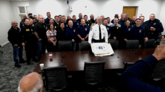 North Brunswick Deputy Police Chief Brian Hoiberg holds a cake with fellow officers by his side following his swearing in.